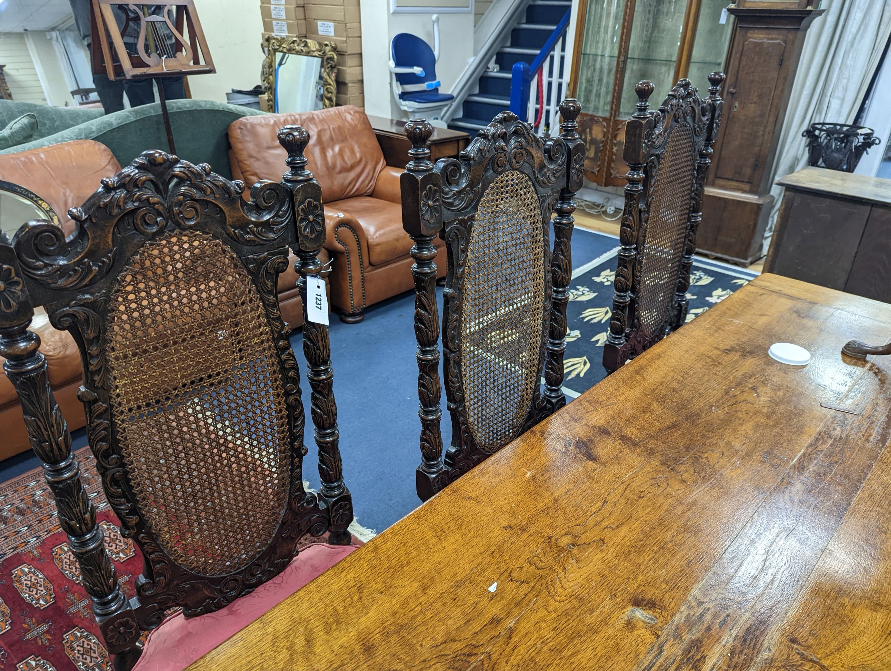A set of six Charles II style carved oak dining chairs with caned backs and seats and squab cushion seats